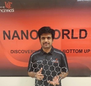 an engineering student poses in front of a sign that reads Nanoworld