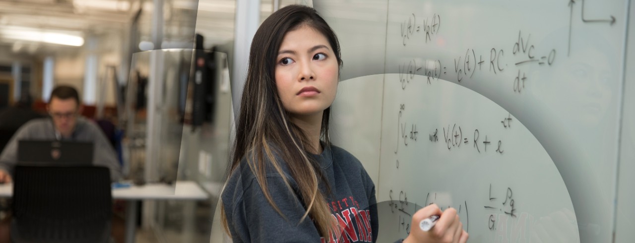 student in classroom writing on white board