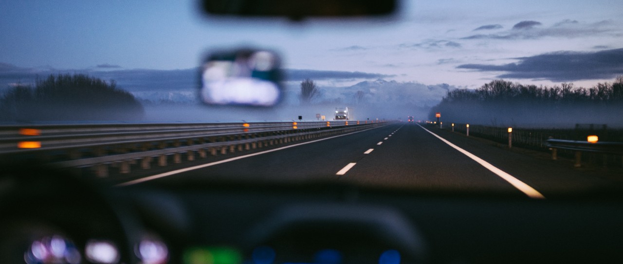 view of a road from inside a car at dusk
