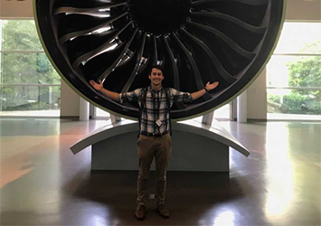 Dustin Carter, aerospace engineering class of 2019, posing in front of a giant jet engine