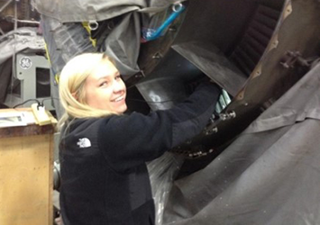 Emily Demjanenko, mechanical engineering class of 2018, is pictured working on a large jet engine while on co-op at GE Aviation.