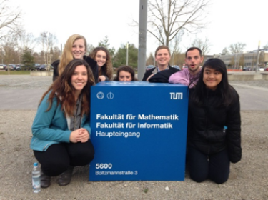 Seven UC students post around a sign at the University of Munich.
