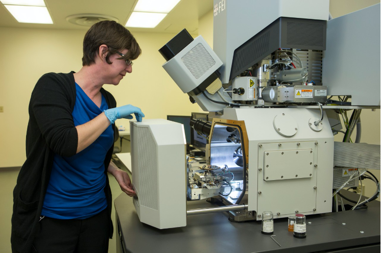 Lab associate working on a large microscope 