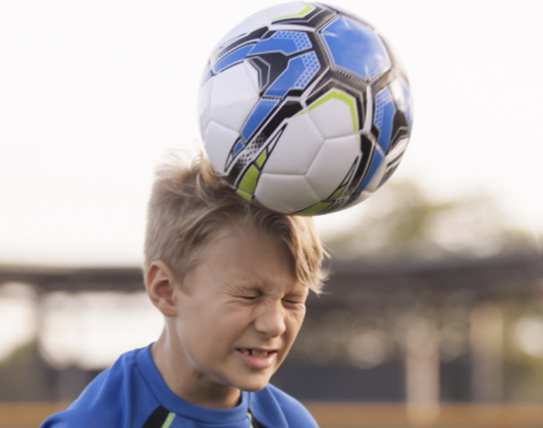 Kid hitting a soccer ball with his head